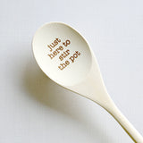Wooden spoon with engraved text 'just here to stir the pot' on a white background